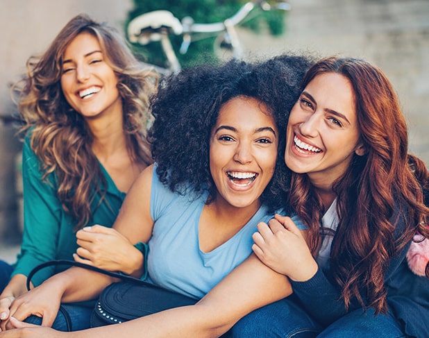 Young group of three women smiling outside