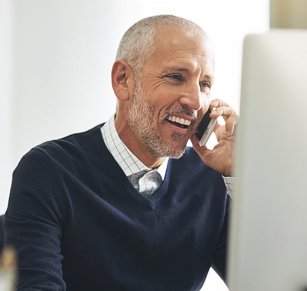 older man smiling while talking on the phone