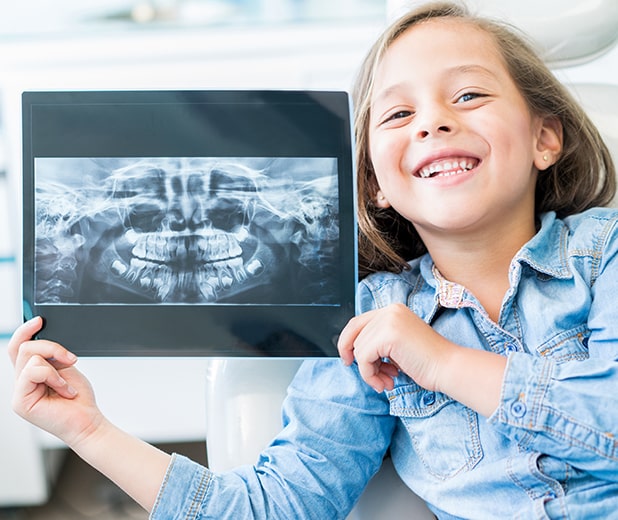 young girl holding her dental x-rays at the dentist's office