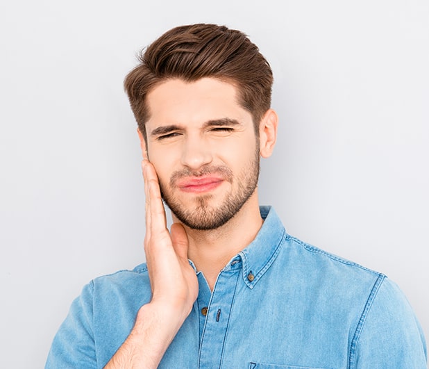 Young man with tooth pain holding his jaw