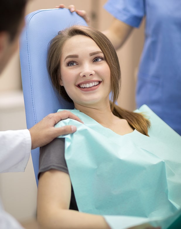 young woman sitting in the exam chair at the dentist's office