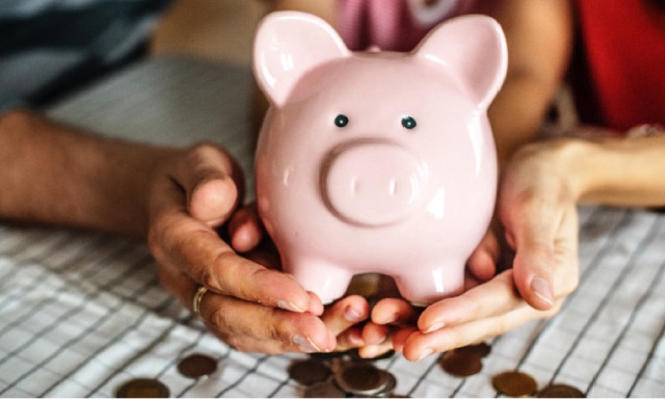 pink piggybank with coins spilling out the bottom