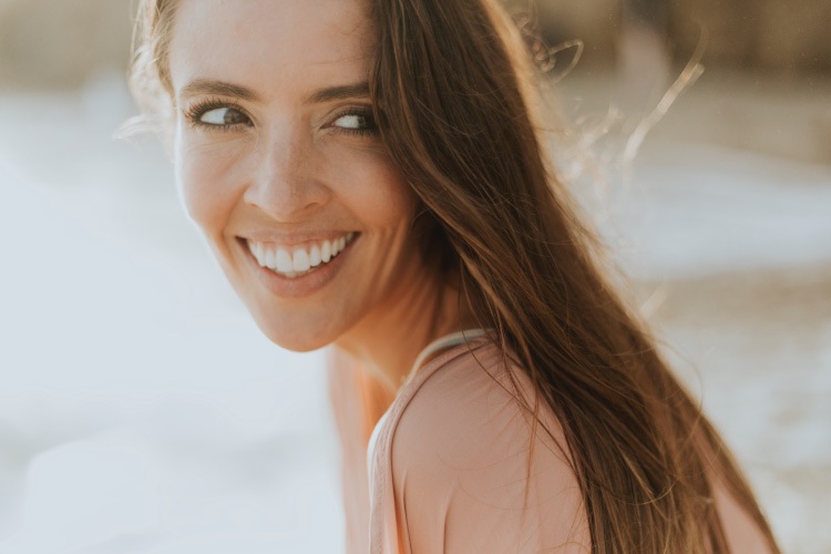 Brunette woman with a bright white smile after teeth whitening smiles happily