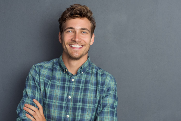 Young man in plaid shirt smiles after discreetly straightening his teeth