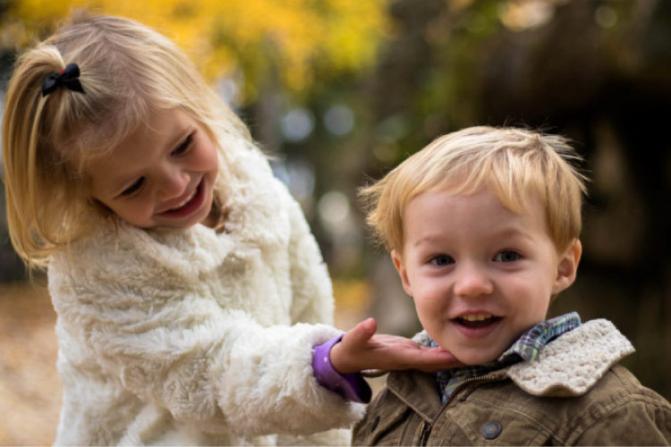 young sister showing off her little brother's baby teeth