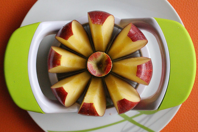 Aerial view of an apple for a lunchbox cored and cute into slices with a green slicer tool