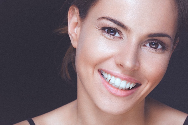 Closeup of a smiling brunette woman with healthy gums and white teeth