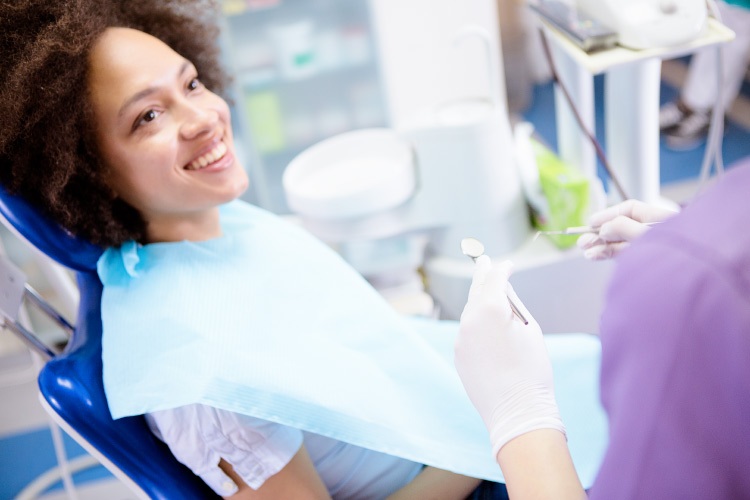 Brunette woman smiles before receiving a safe tooth-colored composite filling at the dentist