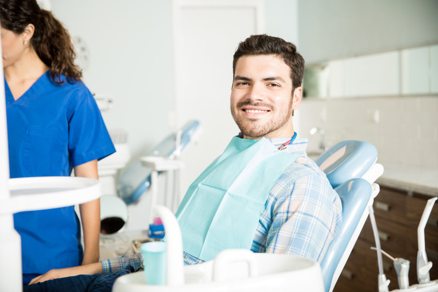 Brunette man in a dental chair smiles after accommodations are made for his allergies at the dentist