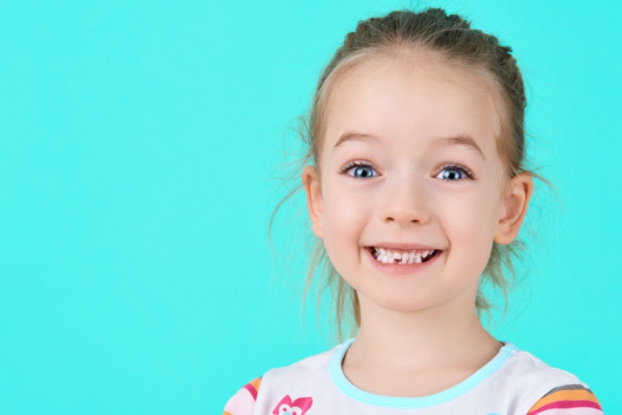 Cute blue eyed smiling little girl on a turquoise background