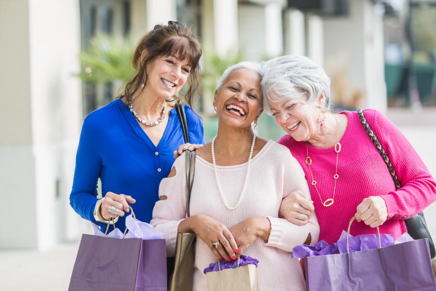 There mature smiling ladies walking down the street together with shopping bags