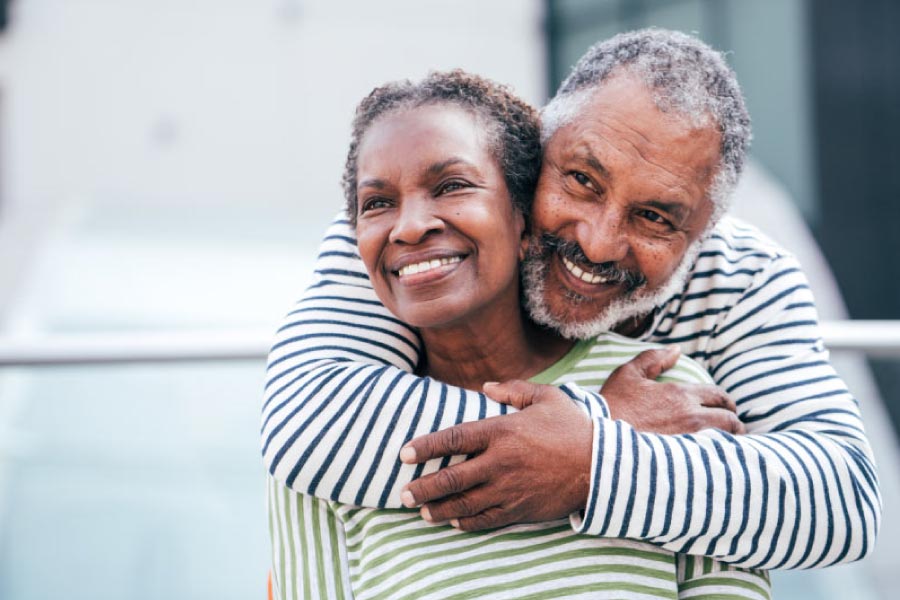 Smiling older black man with his arms around a smiling black woman.