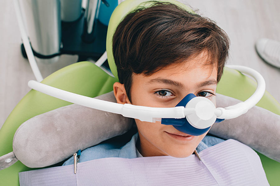 Brown haired boy in the dental chair wearing a nitrous oxide mask.