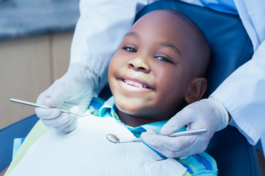 Smiling boy in the dental chair is getting a composite filling.