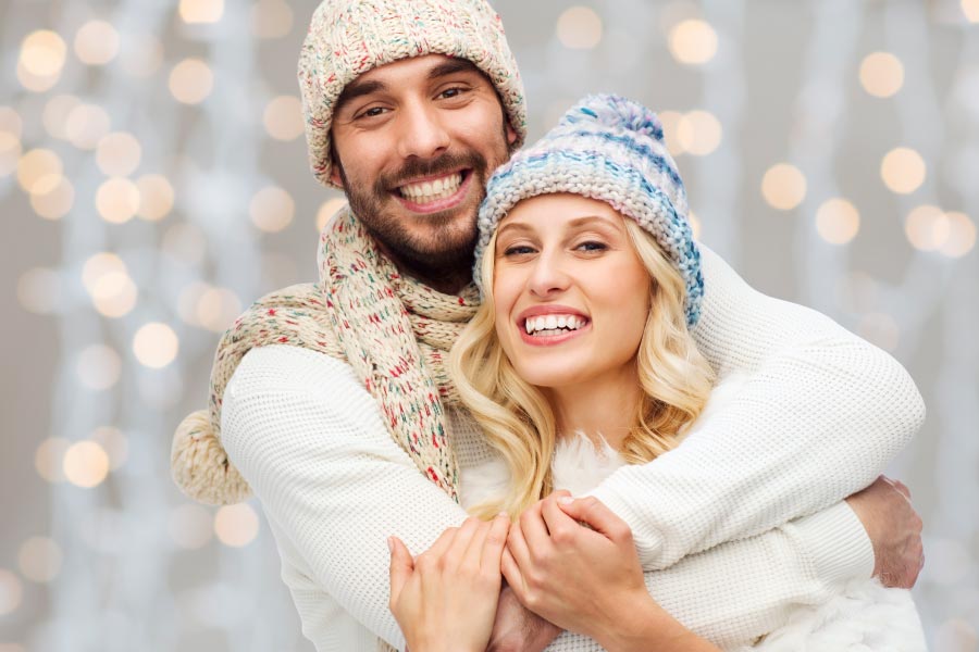 Smiling couple with beautiful teeth wearing winter hats.