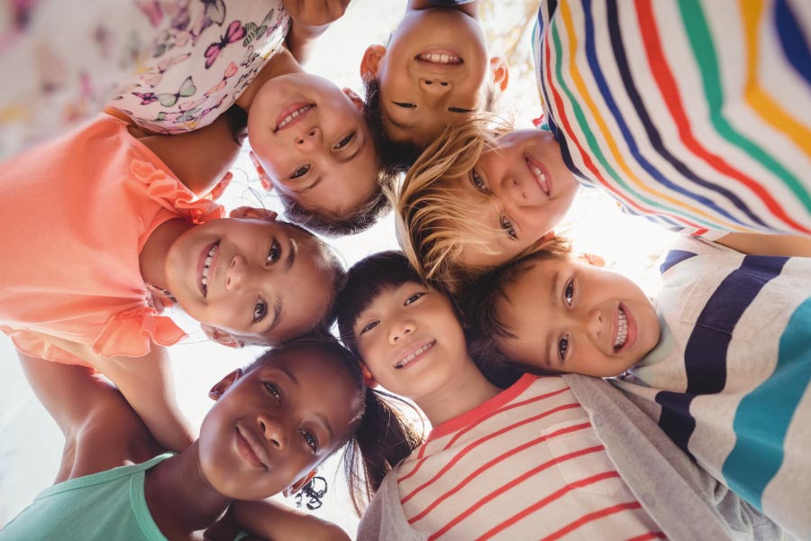 Circle of smiling kids looking down at the camera.