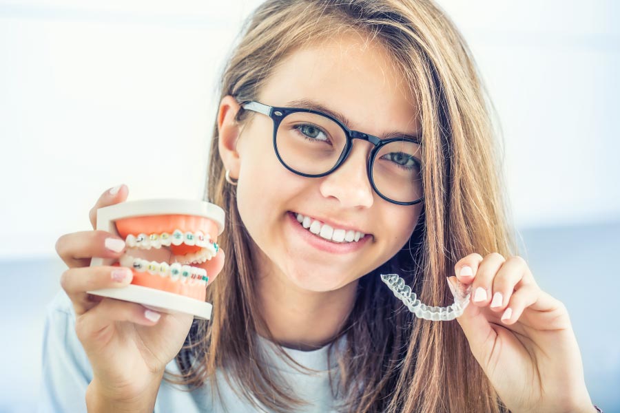 Teen girl holding clear aligners in her hand.