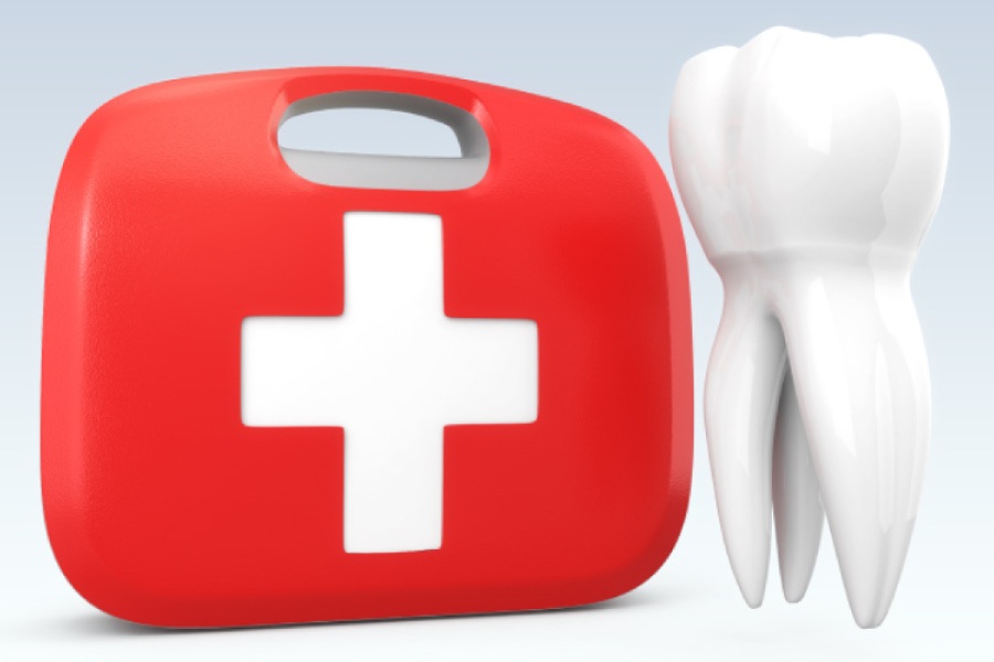 A red emergency kit next to a model of an oversized tooth.