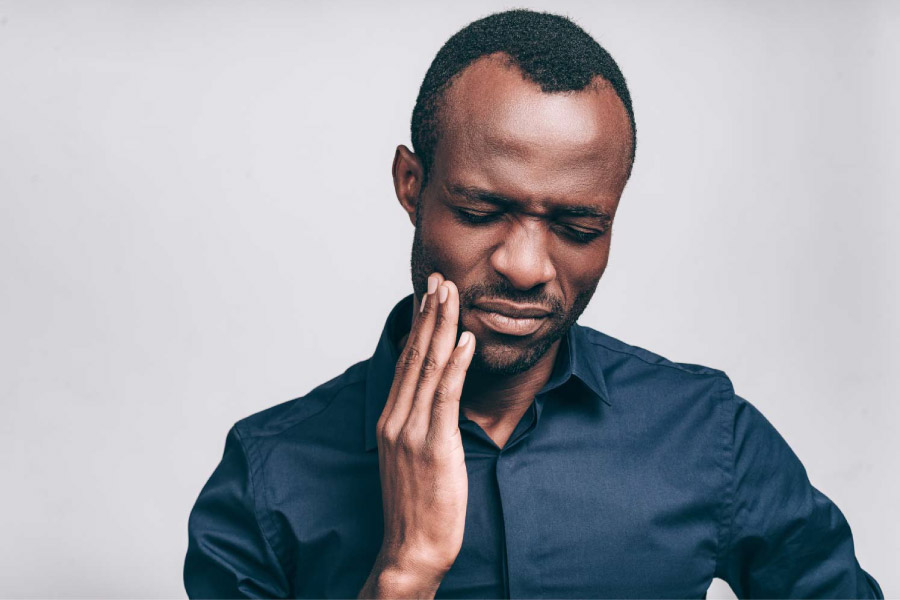 Man with his hand on his cheek due to tooth pain.