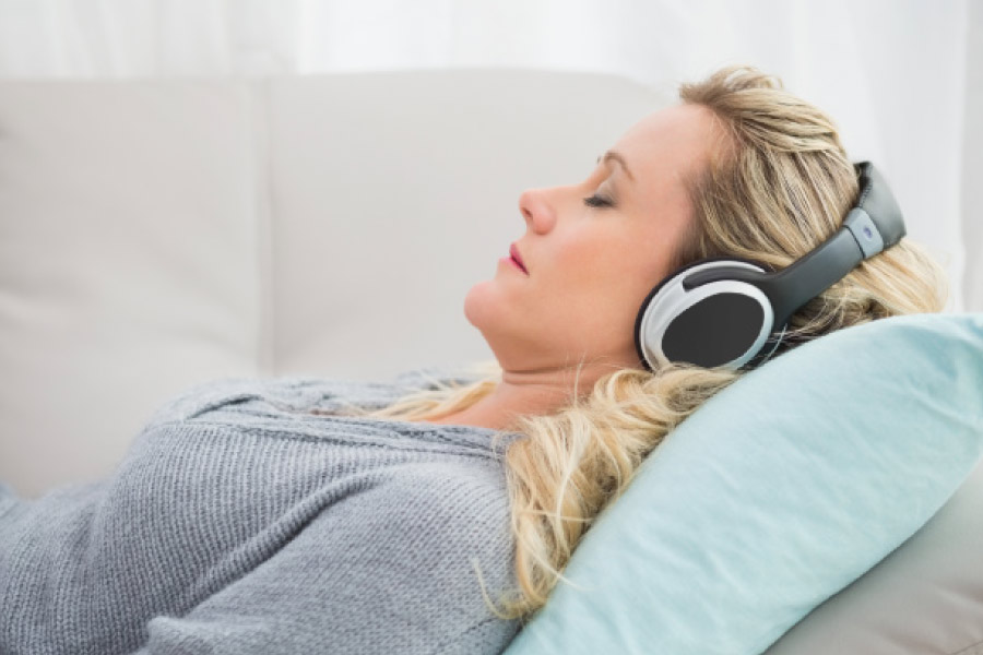 Woman relaxing at the dentist with headphones to ease dental anxiety.