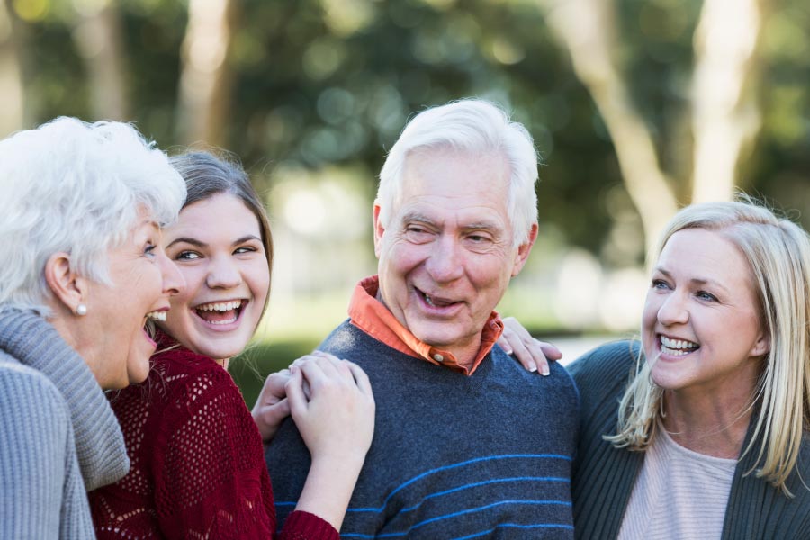 Smiling older couple talking with young adult granddaughters.