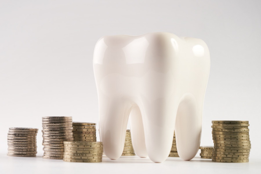 A large model of a tooth next to a stack of coins.