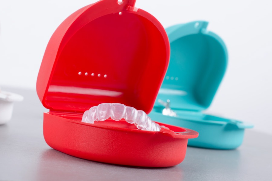 Colorful cases holding Invisalign clear aligners.